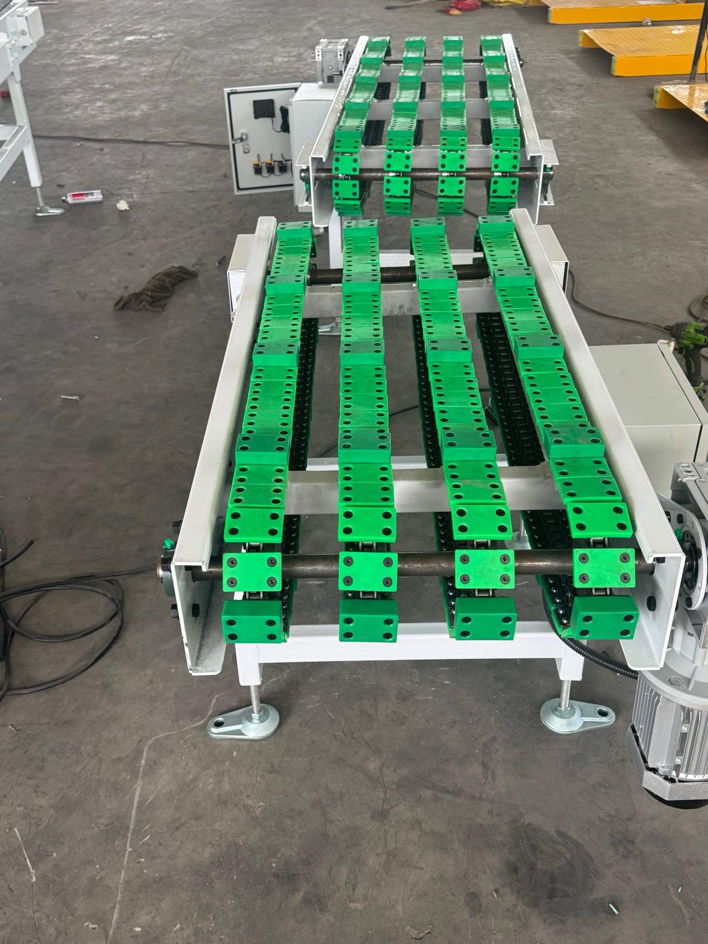 PENKOR chain conveyor — a row of green load carriers on multi-strand chains