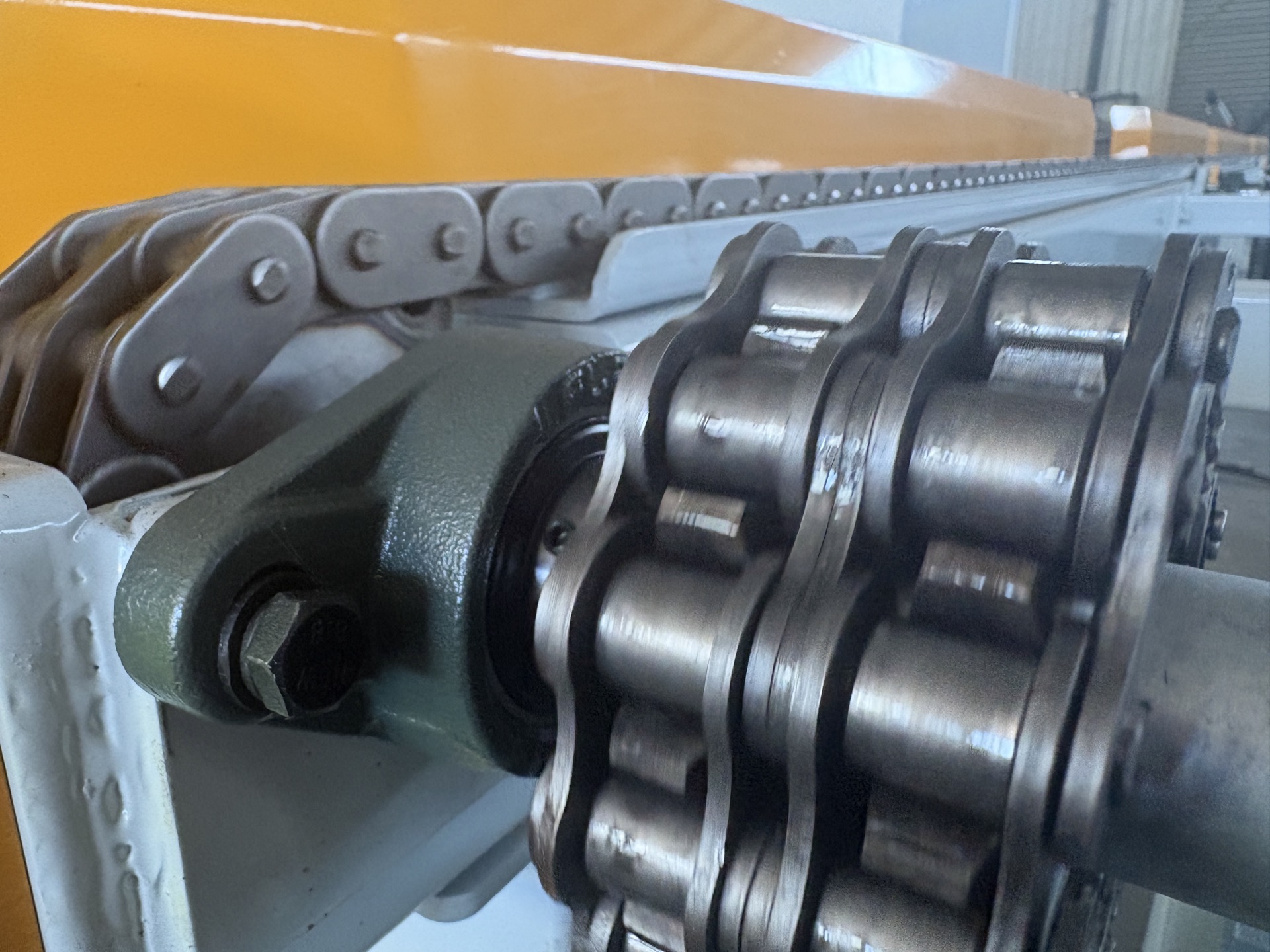 PENKOR drive components shot in the workshop — industrial sprocket with roller chain and bearing housing, close-up