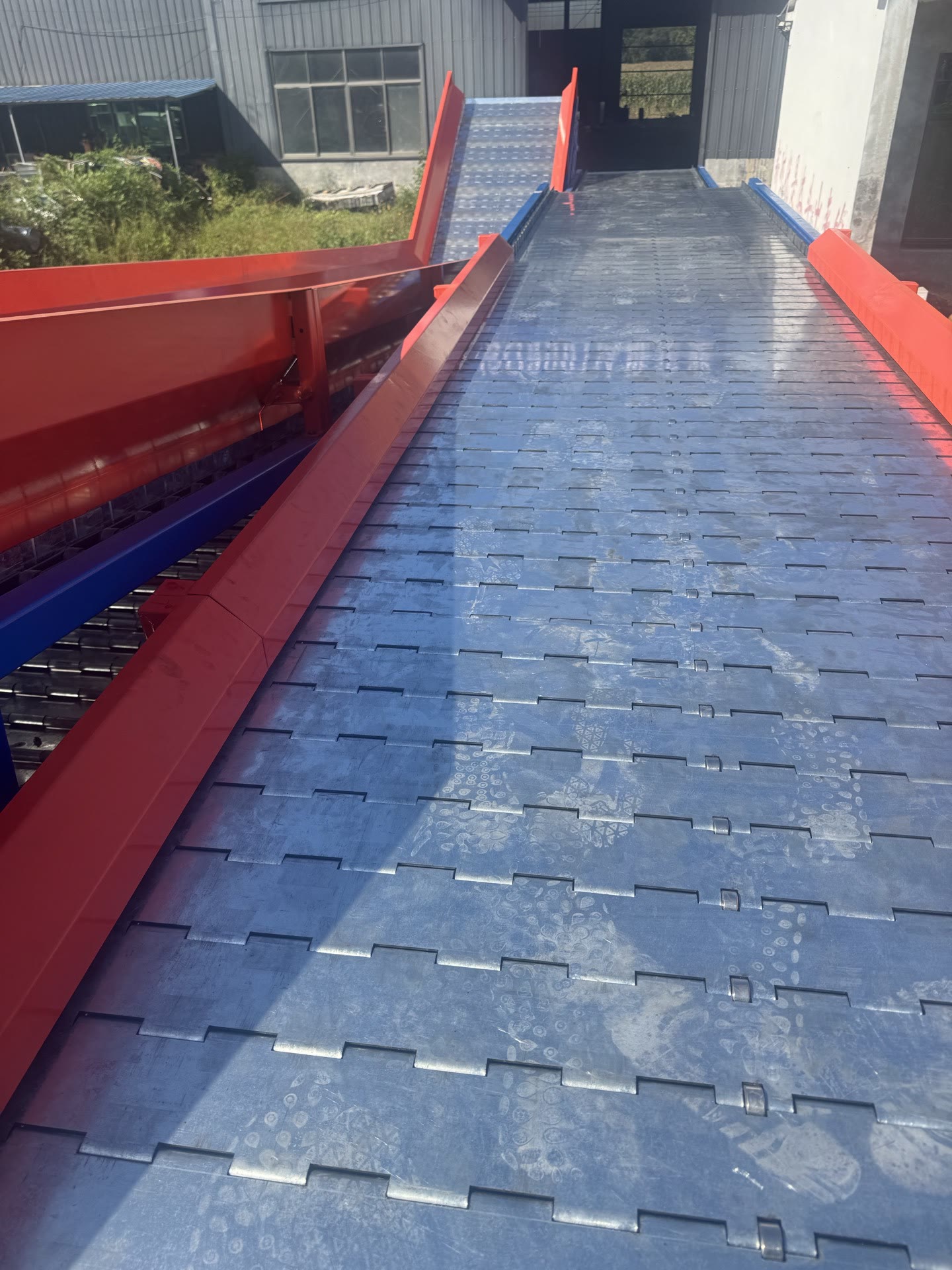 PENKOR slat chain conveyor — red frame with blue chain-plate conveying surface