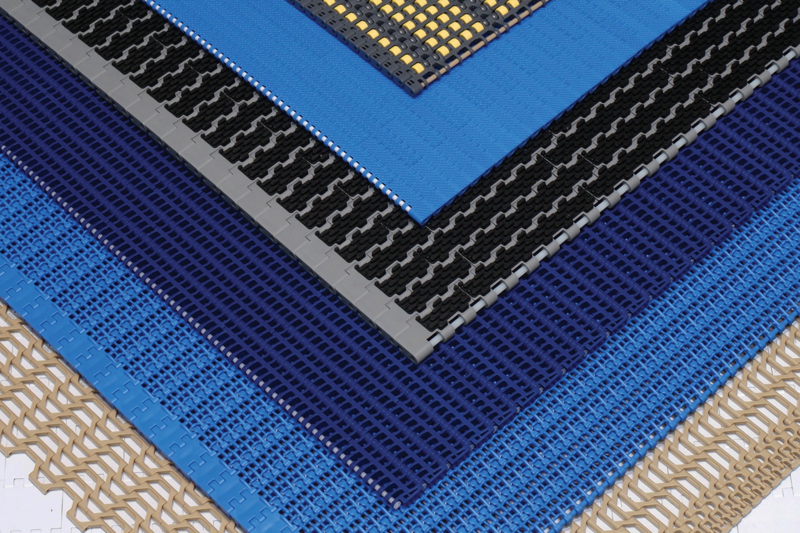 Flat-lay of plastic modular belt samples (blue, black, yellow, tan) (third-party reference photo)