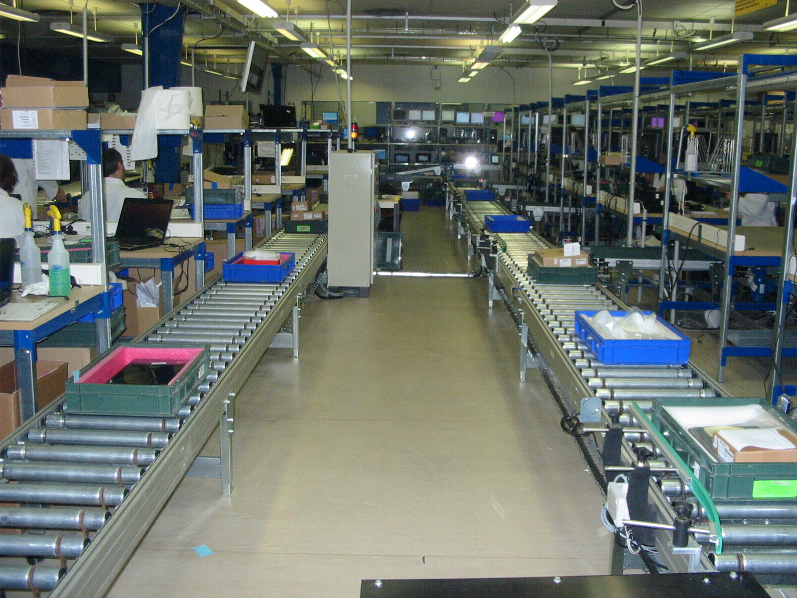 Powered roller conveyor lines carrying plastic totes and cartons through a dispatch hall (third-party reference photo)